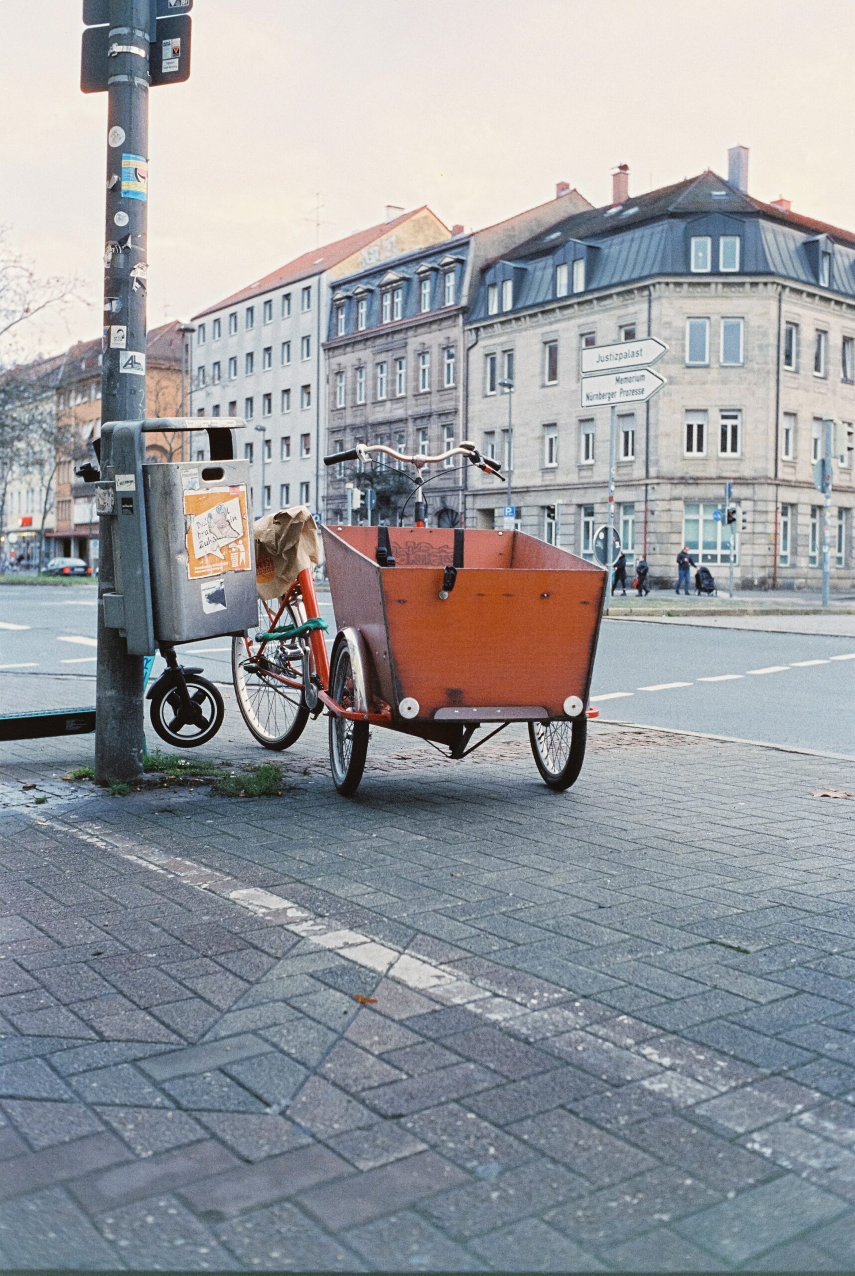 Lastenrad parkt neben Mülleimer auf Fußweg.