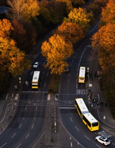 Drei Busse fahren auf relativ leeren Straßen in Berlin-Tiergarten. Es gibt eine Busspur. Die Bäume glühen herbstrot.