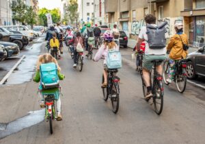 Eine Gruppe von Kindern und Erwachsenen fährt gemeinsam mit dem Fahrrad durch eine Stadtstraße
