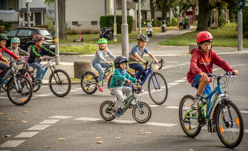 Kinder fahren gemeinsam mit Fahrrädern an einer Kreuzung durch die Stadt